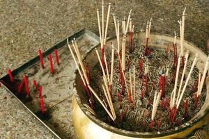 incensario tradicional con palos humeantes dentro de un templo budista. foto