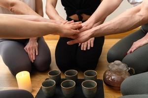 Women friends putting hands together during tea ceremony. photo