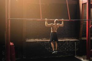 Strong man doing pull up exercise in the gym photo