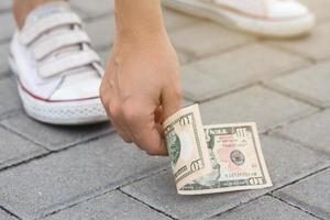 mujer afortunada está recogiendo billetes de diez dólares del suelo. foto
