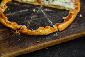 Half of delicious baked pizza on wooden board photo