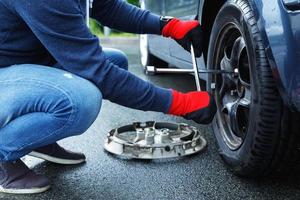Man changing flat tire on his own car photo