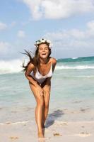 Sexy woman wearing white swimsuit is posing on the beach photo