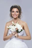 Portrait of young beautiful bride with bouquet of flowers photo