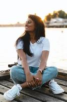 Carefree smiling Indian woman sitting on the wooden pier photo