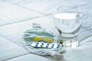 Blister pack of sleeping pills, blindfold and glass of water photo
