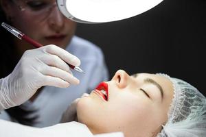 Permanent makeup artist and her client during lip blushing procedure photo