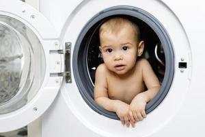 niño curioso sentado dentro de la lavadora foto