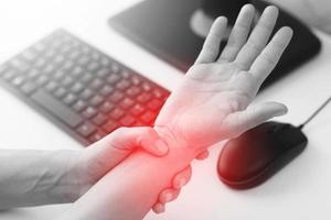 Woman working in office with a carpal tunnel syndrome or wrist joint inflammation photo