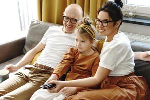 Happy family watching TV show together sitting on the couch photo