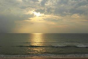 Sunset on the beach. Scenic seascape with clouds, waves and sun. photo