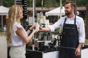 hombre barista dando una taza de café a una mujer cliente foto