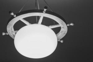 Monochrome photo of vintage lamp decorated with ship's wheel