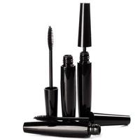 Black mascara brushes and containers on white background photo