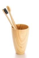 cepillos de dientes de bambú dentro de la taza de madera en blanco foto