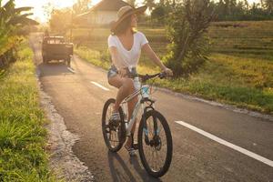 la mujer está montando en bicicleta por un camino rural estrecho foto