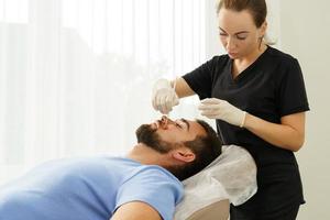 Young man during peeling treatment in beauty clinic photo