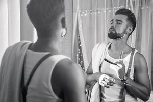 Man looking in the mirror and shaving his beard with a straight razor photo