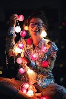 Happy woman wearing glowing jacket with sequins is holding light balls in her hands photo