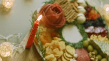 Flat charcuterie with salami, different kinds of cheese. It has dried fruits, various nuts and honey. Holiday arrangement with burning candles video