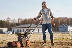 hombre que usa una máquina aireadora para escarificar y airear el césped o la pradera foto