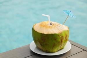 bebida de coco en la mesa junto a la piscina foto