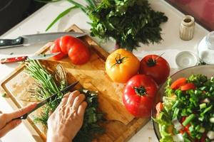 Woman chopping parsley and dill for healthy vegetarian salad photo