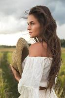 mujer encantadora joven que sostiene el sombrero de paja en el campo de arroz foto