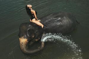 mujer feliz se está bañando con el elefante en el río