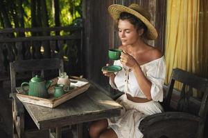 Happy woman sitting on the summer terrace and drinking coffee photo