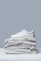 Stack of white clothes and stylish trainers photo