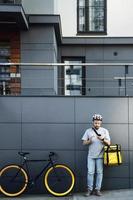 Express food delivery courier with insulated bag looking at phone. photo