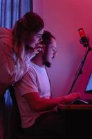 Young couple in room with neon light are using modern personal computer photo