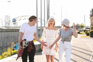 Three happy teenage friends are walking in a city photo