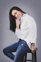 Beautiful middle aged woman wearing white shirt and jeans in photo studio