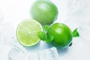 Fresh lime fruits with mint and ice cubes photo