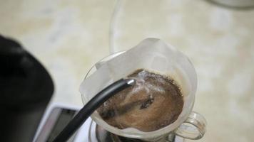 video mientras se vierte agua hirviendo caliente en granos de café recién molidos para hacer café de goteo hecho en casa para la bebida de la mañana del desayuno