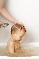 madre lavando y duchando a su pequeño hijo. foto