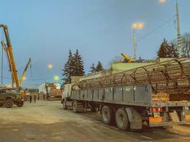 construction of a broken bridge on a busy road. a heavy truck brought to the site a metal building frame for the bridge photo