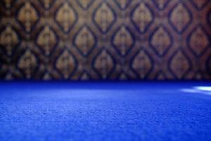 suelo de moqueta azul en un enfoque selectivo con un fondo de arte mural tradicional tailandés borroso, adecuado para el telón de fondo de la presentación del producto, la exhibición y la maqueta. foto