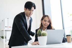 Business people discuss business ventures together by viewing information through a notebook photo