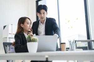 Business people discuss business ventures together by viewing information through a notebook photo