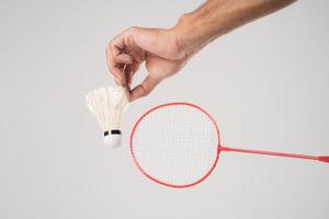 A badminton player in sportswear stands holding a racket and shuttlecock. photo