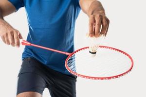 A badminton player in sportswear stands holding a racket and shuttlecock. photo