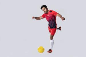 jugador de fútbol profesional en pose de uniforme de entrenamiento rojo sobre un fondo blanco concepto de fútbol activo. foto