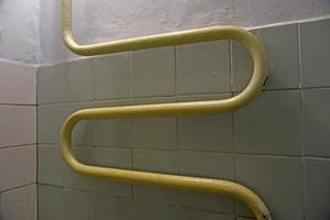 Iron twisted pipe in the form of a heating battery in the bathroom. Radiator heater in the room. photo