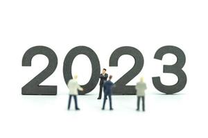2023 Business New Year Concept. Closeup of group of businessman miniature figures standing with number on white background. photo