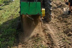 Harvesting in the village, harvesting potatoes with a tractor with a plow and a vibrating screen. photo