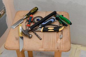 las herramientas de trabajo yacen en orden caótico en la silla, reparaciones en la casa. foto