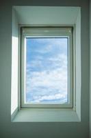 Closed roof window through which you can see the blue sky and white clouds on a sunny day. Bottom view. photo